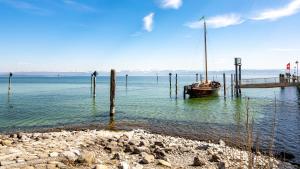 a boat sitting in the water next to a dock at Auszeit vom Alltag- schöne, moderne Wohnung am See in Immenstaad am Bodensee
