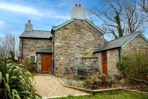 an old stone house with a table and chairs at Hallgarden Farmhouse in Otterham