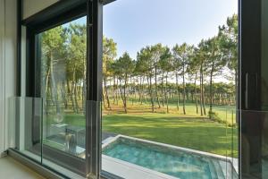 une fenêtre avec vue sur la piscine et les arbres dans l'établissement Villa Palm Green, aux Mathes