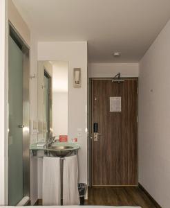 baño con lavabo y puerta de madera en Hotel Hi! Guadalupe, en Monterrey