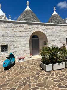 a stone building with a blue scooter in front of it at Trullo in vigna in Cisternino