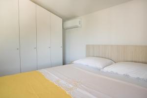 a bedroom with a white bed with a yellow blanket at Apartments Diva in Ston