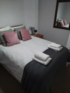 a large white bed with two towels on it at Apartment in Boscombe close to beach in Bournemouth