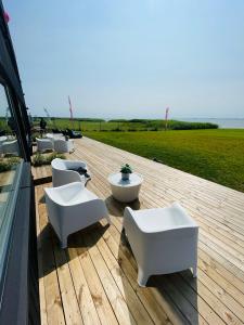 une rangée de chaises et de tables blanches sur une terrasse dans l'établissement Aitvarai 41, à Svencelė