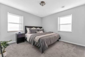 a white bedroom with a bed and two windows at Maple Heights Getaway in Maple Heights