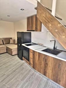 a kitchen with wooden cabinets and a sink and a couch at Suloti House Lungomare in Vlorë