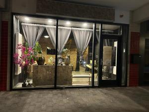 uma frente de loja com uma janela com cortinas e flores em Privespa hotel Little escape em Wormer