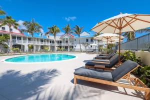 a resort pool with lounge chairs and an umbrella at Alamanda Studio n°6 / Beachfront Res - Orient Bay in Orient Bay