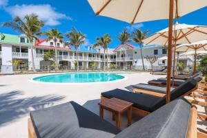 a resort pool with lounge chairs and umbrellas at Alamanda Studio n°6 / Beachfront Res - Orient Bay in Orient Bay