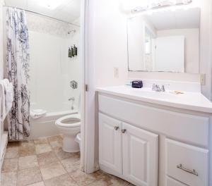 Baño blanco con lavabo y aseo en Acadia Pines Motel, en Bar Harbor