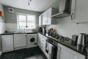 a kitchen with a stove and a washer and dryer at BRIARS CLOSE - Four Bed Property on the Edge of the Peak District National Park in Buxton
