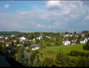 una pequeña ciudad con casas y una iglesia en una colina en Ferienwohnung & Zimmer en Olpe