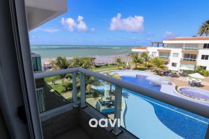 a view of the pool and beach from the balcony of a resort at Cobertura de Luxo em Resort Beira Mar - Qavi in Búzios