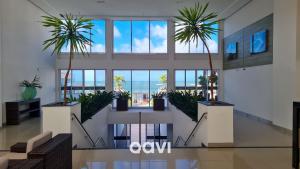 a lobby with two palm trees in a building at Cobertura de Luxo em Resort Beira Mar - Qavi in Búzios