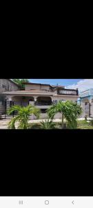 a building with palm trees in front of it at Bobby Vacation Home in Portmore