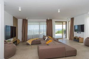 een woonkamer met een bruine bank en een televisie bij Villa Ventus in Šmrika