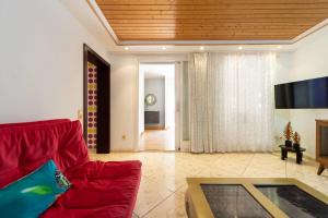 a living room with a red couch and a tv at Los Jardines del Cura in Playa del Cura