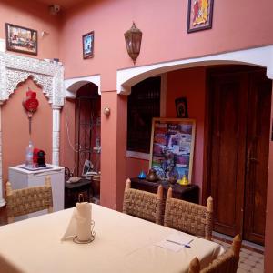 une salle à manger aux murs roses avec une table et des chaises dans l'établissement Riad Tifor, à Marrakech