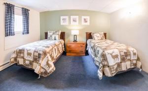 a bedroom with two beds and a wooden dresser at Acadia Pines Motel in Bar Harbor