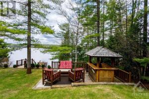 a gazebo with chairs and a gazebo with a table at Macwan's Lakefront Cottage in Calabogie