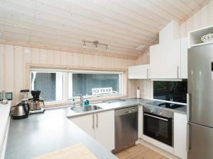 uma cozinha com armários brancos e um frigorífico de aço inoxidável em Holiday home Slagelse XLVII em Slagelse