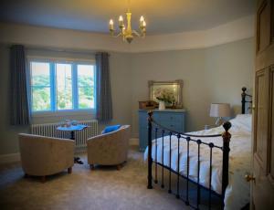 a bedroom with a bed and two chairs and a window at The Old Rectory with Valley View in Stockton on Teme
