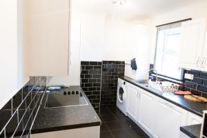 a kitchen with white cabinets and a washer and dryer at Gillingham Two bedroom house with garden and free parking in Gillingham