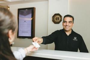 Um homem está a dar um controlo remoto a uma mulher. em Corona Hotel & Spa em Ensenada