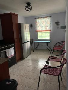 eine Küche mit 2 Stühlen, einem Tisch und einem Kühlschrank in der Unterkunft Casita Nieves in Isabela