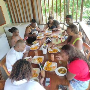 Eine Gruppe von Menschen, die an einem Tisch sitzen und Essen essen. in der Unterkunft Cabañas las perlas in Bahía Solano