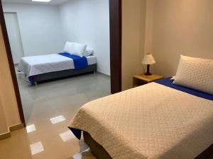 1 dormitorio con 2 camas y lámpara. en Aparta Hotel Montealegre, en Bogotá