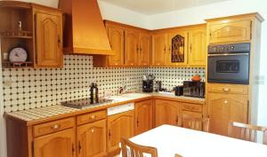 La cuisine est équipée de placards en bois et d'un four avec plaques de cuisson. dans l'établissement Maison de ville calme, à La Roche-sur-Yon