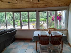 Una sala de estar con mesa y sillas y ventanas. en Moira Cottages @Berwickhall Sleeps 12, en Moira