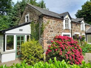 Una casa de piedra con flores delante de ella. en Moira Cottages @Berwickhall Sleeps 12, en Moira