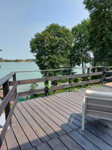 a bench sitting on a wooden deck next to the water at Apartamenty nad jeziorem in Mikołajki