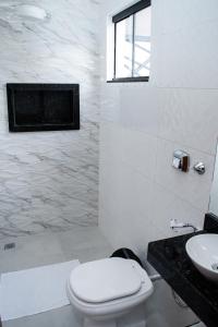 a white bathroom with a toilet and a sink at Aquarela Apart Hotel in Sinop