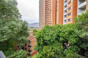 uma árvore em frente a um edifício alto em Apartamento a 3 min del Hospital Pablo tobón uribe em Medellín