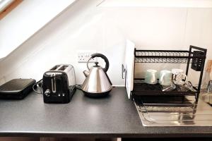 a kitchen counter with a tea kettle and coffee cups at Stylish flat in London with free parking in London