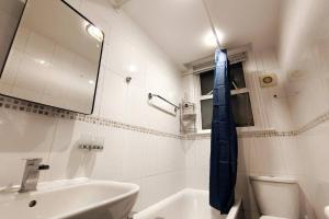 a white bathroom with a blue tie hanging on the wall at Stylish flat in London with free parking in London