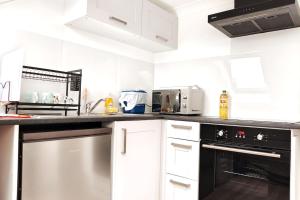 a kitchen with white cabinets and black appliances at Stylish flat in London with free parking in London