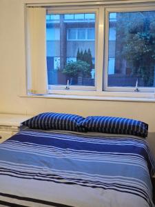 a bed with two pillows in front of a window at Axel room 2 in Manchester
