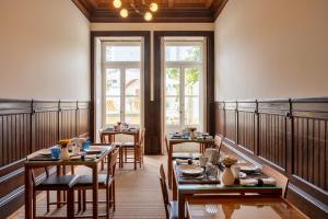 uma sala de jantar com mesas, cadeiras e janelas em Casa do Arquiteto - Townhouse - Architect's House no Porto