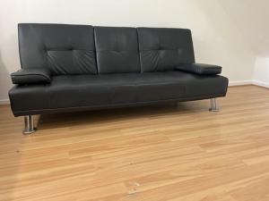 a black couch in a room with a wooden floor at Ensuite With Kitchen Ext Large Room With Balcony in Zone 2 in London