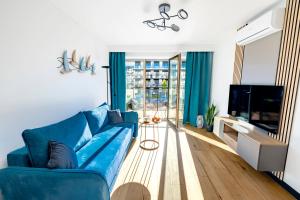 a living room with a blue couch and a tv at Apartament Opal - Family & SPA in Dziwnów