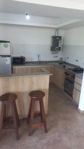 a kitchen with a counter and two stools in it at Descanso en Las Acequias in Roldán