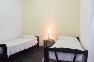 two beds in a room with a lamp on a table at Del Fundador in San Luis