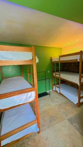 three bunk beds in a room with a green wall at Sunsand Beach Suítes e Hostel in Camocim