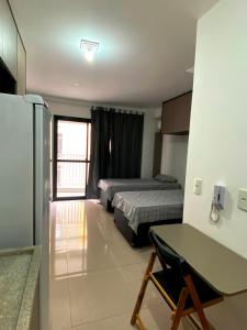 a room with two beds and a desk and a refrigerator at Studio APaulistana56 in Sao Paulo