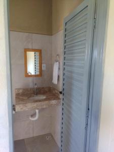 uma casa de banho com um lavatório e um chuveiro com um espelho. em Chalé pôr do Sol em Alto Paraíso de Goiás