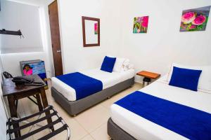 een hotelkamer met 2 bedden, een tafel en een bureau bij Hotel Casa 10 in Medellín